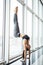Sporty yoga girl on white background doing a handstand in pose shirshasana with entwined legs against panoramic windows