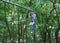 Sporty, young, cute boy in white t shirt spends his time in adventure rope park in helmet and safe equipment in the park