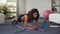 Sporty young female setting stopwatch, doing plank exercise and checking time