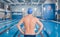 Sporty young man in the swimming pool preparing to swim , rear view