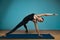 Sporty young woman doing stretching. Slim girl practicing yoga indoors on blue background. Calm, relax, healthy