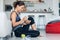 Sporty young woman eating a bowl of muesli while listening music sitting on the floor at home