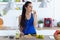 Sporty young woman eating lime slice while preparing detox beverage in the kitchen at home