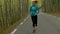 Sporty young woman running on mountain road in beautiful nature.