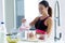 Sporty young woman serving strawberry smoothie in a glass jar in the kitchen at home