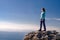 Sporty young woman sitting in a rocky top of the mountain against the blue of sky and sea