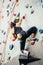 Sporty young woman training in a colorful climbing gym. Free climber girl climbing up indoor