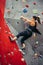 Sporty young woman training in a colorful climbing gym. Free climber girl climbing up indoor