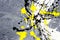 A spot of white and black and yellow spilled paint on a concrete textured surface