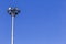 Spotlights tower high voltage in sport stadium on blue sky background