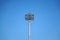 Spotlights tower with a metal pole for the sports arena. Installed around football stadium. Blue sky background.