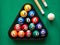 Spots and stripes balls in triangle, cue ball and two cues on the green table. Mini billiard, pool or snooker