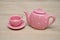 A spotted pink porcelain tea cup and kettle