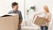 Spouses Laughing And Joking Carrying Moving Boxes In New Home
