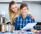 Spouses signing documents and smiling at kitchen