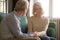 Spouses sitting on couch elderly husband comforting sad woman