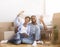 Spouses Using Tablet Sitting Among Moving Boxes Discussing Renovation Indoor