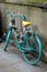 A spray painted green bike decorated with colourful flowers stands next to a wall