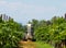 A sprayer machine, trailed by tractor, sprinkles pesticides among the rows of vineyards . Back view