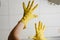 Spread fingers in yellow washing rubber gloves