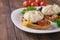 Spreading poached eggs on a white plate on a wooden table.