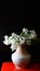 Sprigs of white lilac on a dark background in a ceramic vase.