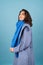 Spring autumn portrait of a woman in a blue knitted sweater, scarf and gray coat