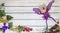 Spring background flat lay of white planks with glass grapes and a purple fairy