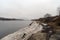 Spring Bank of the river with the remains of dirty melting snow on cloudy day