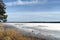 Spring bay Bank in forest with remains of melting ice floes with snow on sunny day