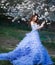 Spring Beautiful romantic haired girl in blue lace dress standing in blooming garden with owl.