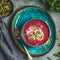 Spring beetroot soup on bright blue plate over gery background