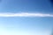 spring blue sky with a thin strip of clouds. bright blue sky and a band of clouds horizontally