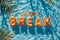 Spring break word spelled out in inflatable pool floats in a summer holiday swimming pool