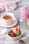 Spring Breakfast with granola and fresh strawberries and lychee and flowers on wooden background