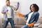 Spring-Cleaning Fun. Joyful African Couple Fooling Together While Tidying Their Apartment