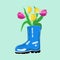 Spring composition made of blue rubber boot and bunch of tulips