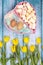 Spring composition of yellow flowers, a tulip, a basket of sweets and eggs on a blue background. Congratulations on Easter.