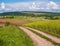 Spring countryside view with dirty road, rapeseed yellow blooming fields, village, hills. Ukraine, Lviv Region