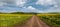 Spring countryside view with dirty road, rapeseed yellow blooming fields, village, hills. Ukraine, Lviv Region