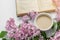 Spring cozy composition flat lay coffee cup, book, lilac branches, spring season concept