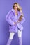 Spring fashion. Beautiful happy blonde woman in lilac fur on a purple background in studio. Pretty model is wearing a stylish vio