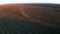 Spring field work, tractor cultivates land in the light of sunset, aerial video