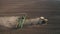 Spring field work, a tractor with a mounted seeder sow seeds in the ground on an agricultural field