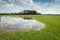 Spring flooded meadow, forest on the horizon and clouds in the sky