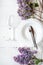 Spring floral table settings with spring flowers. Top view. Plates, wine glass and cutlery with decorative textile on white wooden