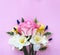 Spring flower arrangement. Yellow daffodils, pink astromeria and a large scarlet rose on a light pink background.