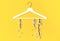 Spring flowering branch hang white wooden hangers on yellow background. Spring sale concept discount store shopping empty hanger