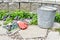 Spring flowers in early season garden with tools and weeding pail ready for garden maintenance