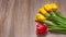 Spring flowers.Four yellow and one red tulip on a wooden background.
